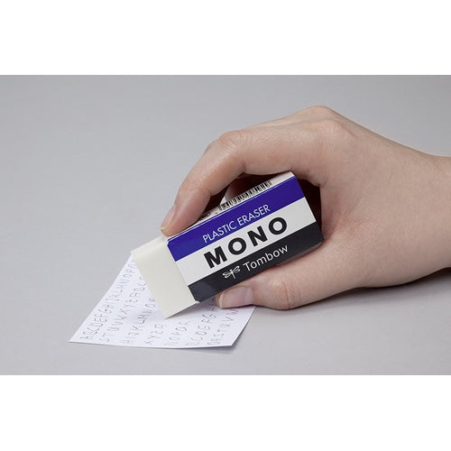 Hand holding Tombow Mono eraser demonstrating erasing pencil marks on paper